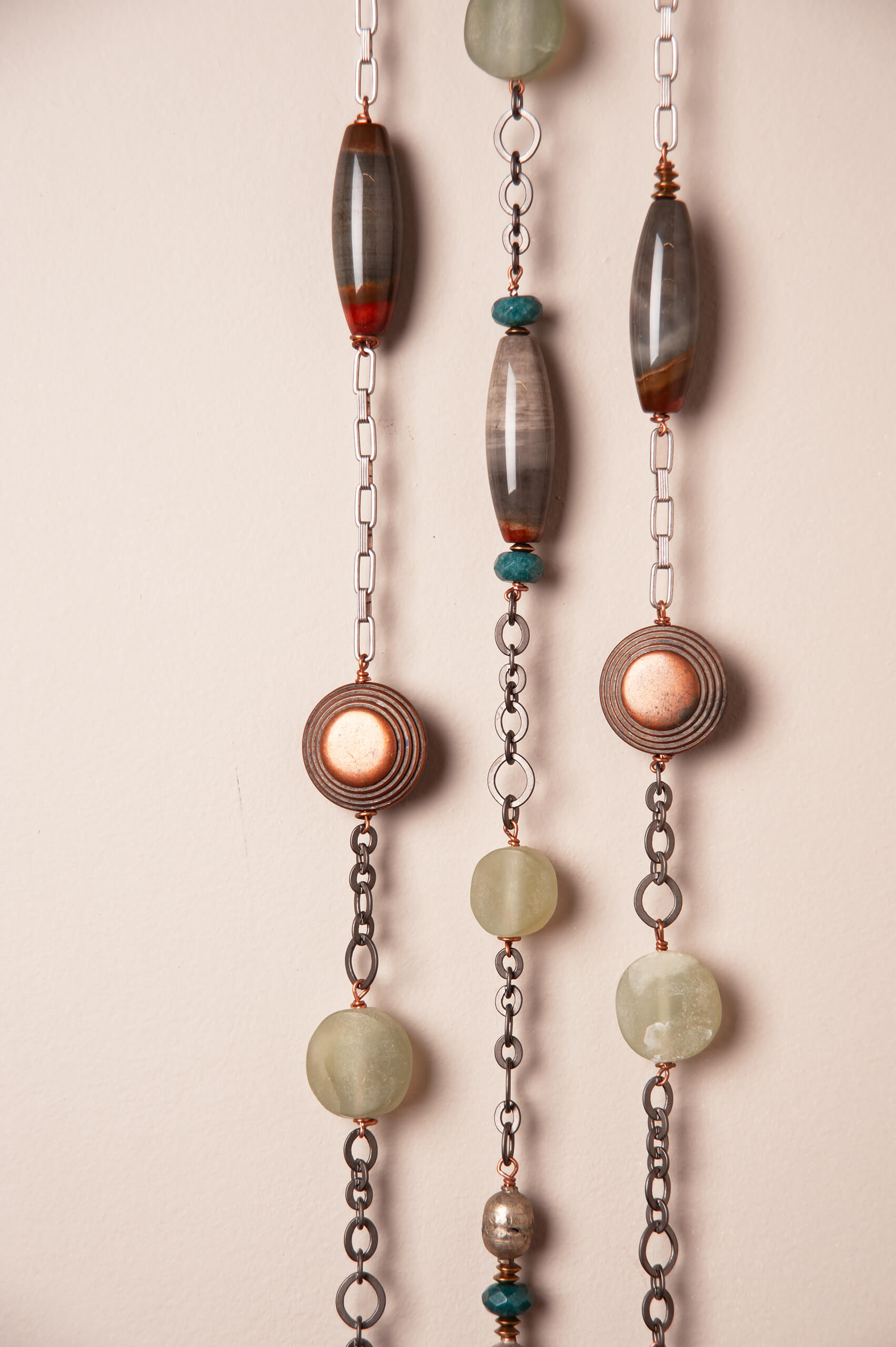 Close up of three cascading stone strands showing ocean picture jasper, green jade and green onyx with copper beads and gunmetal silver metals
