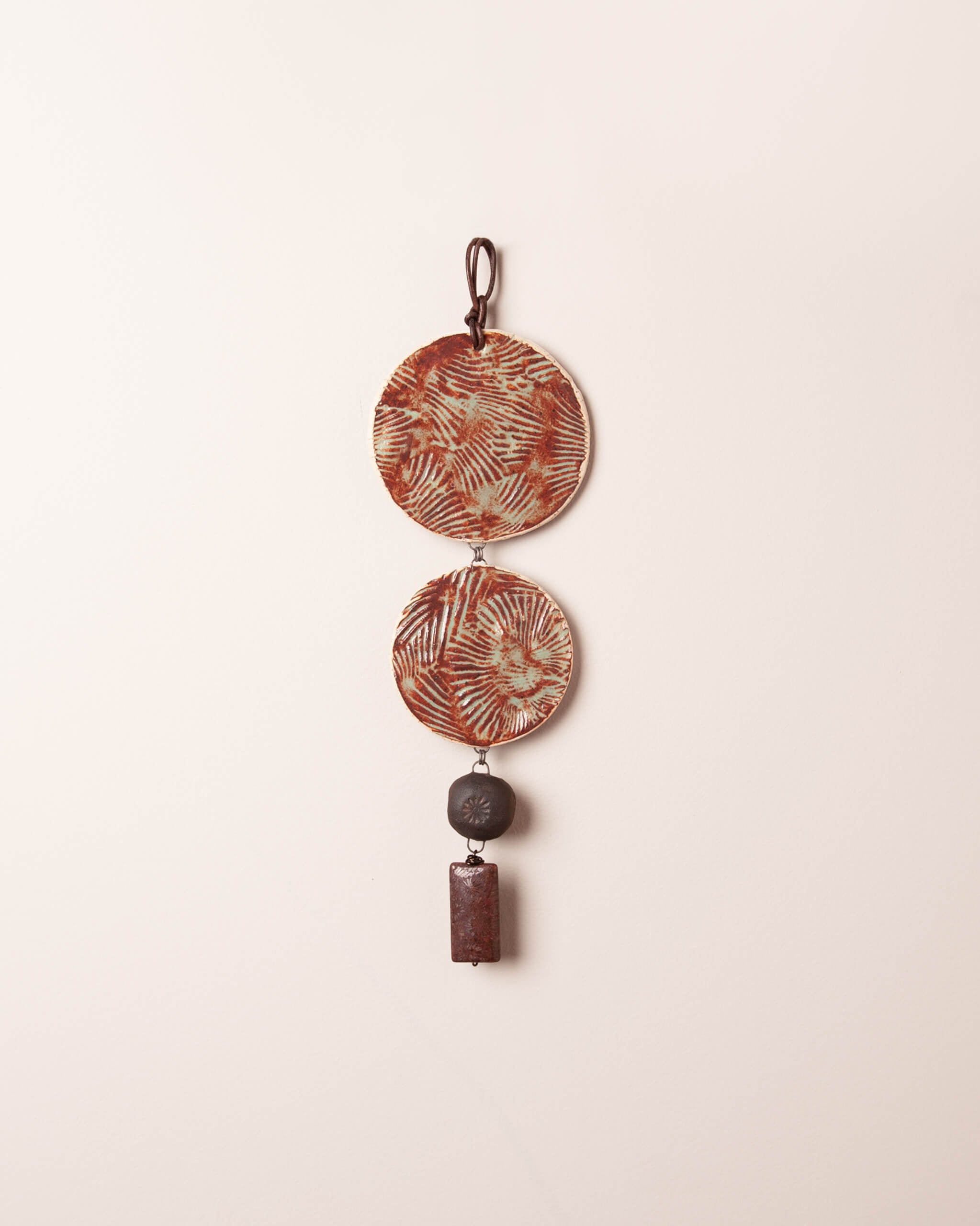 Shore Night Cascade handmade ceramic wall hanging with shell texture discs, dark night clay flower bead and fossilized coral agate drop, made in the Santa Cruz Mountains of California