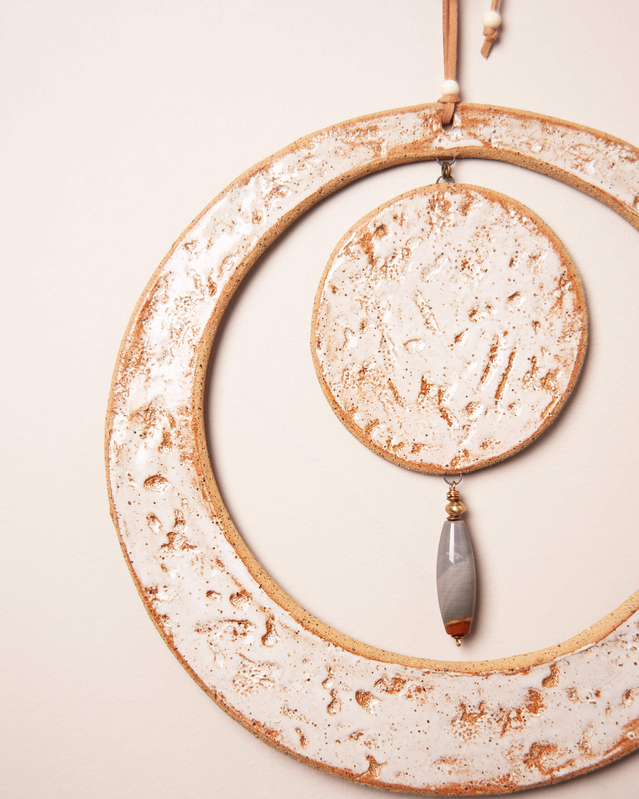 Close up of abalone and coral texture impression in white frost glazed sandy ceramic clay with ocean picture jasper pendant and bronze accents