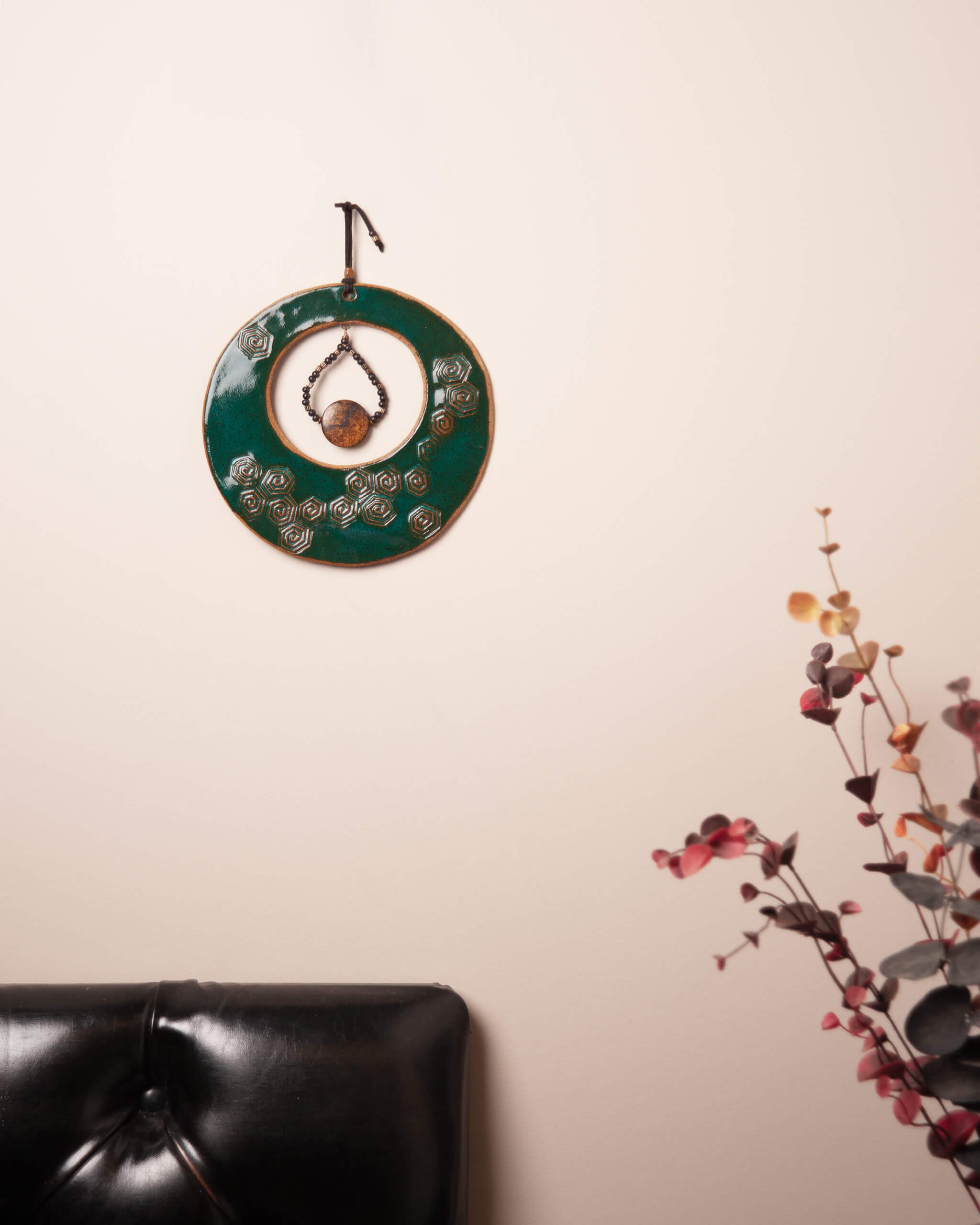 Spiral Tide Moon ceramic wall hanging displayed in home setting showing full emerald green glaze and spiral pattern detail