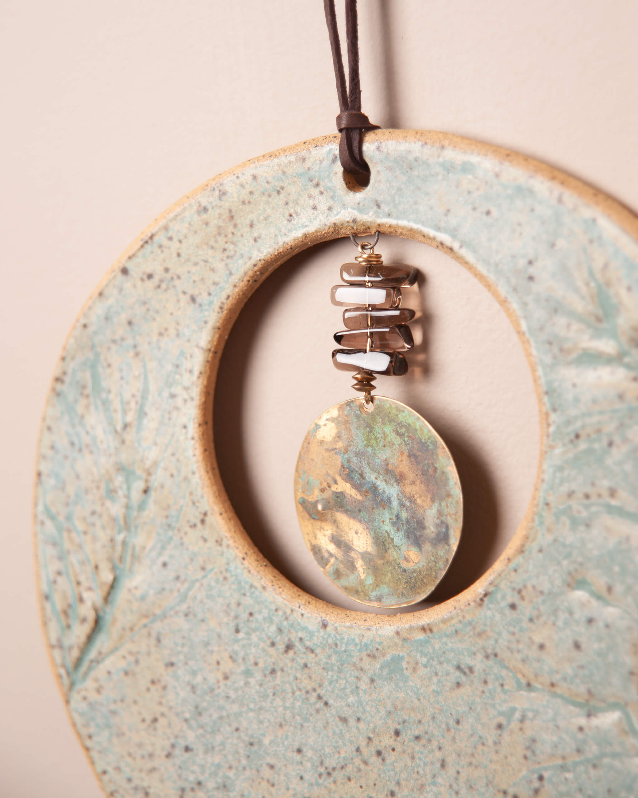 Close up of monkey flower impression in sandy speckled ceramic clay with patinated brass and smoky quartz center stone