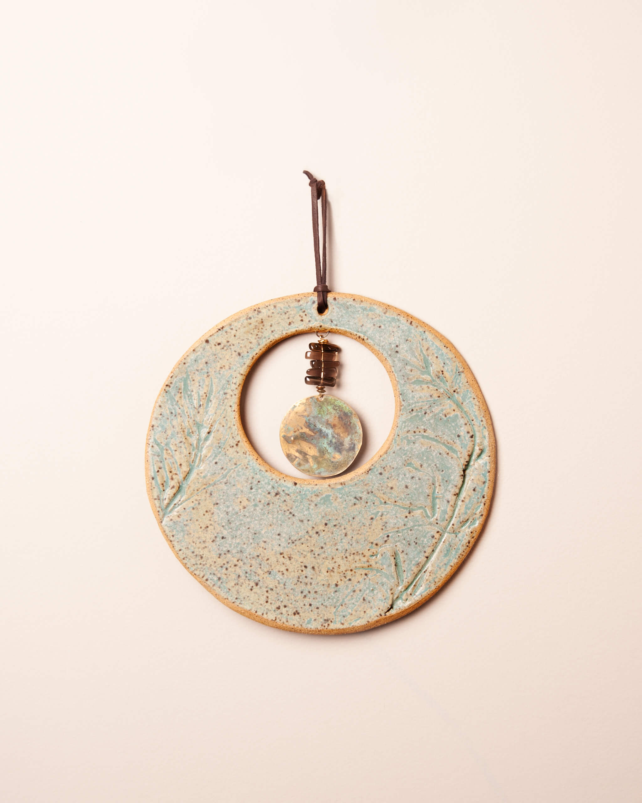 Wild Sage Moon handmade ceramic wall hanging with monkey flower impression, sage and turquoise patina glaze, and smoky quartz pendant, made in the Santa Cruz Mountains of California