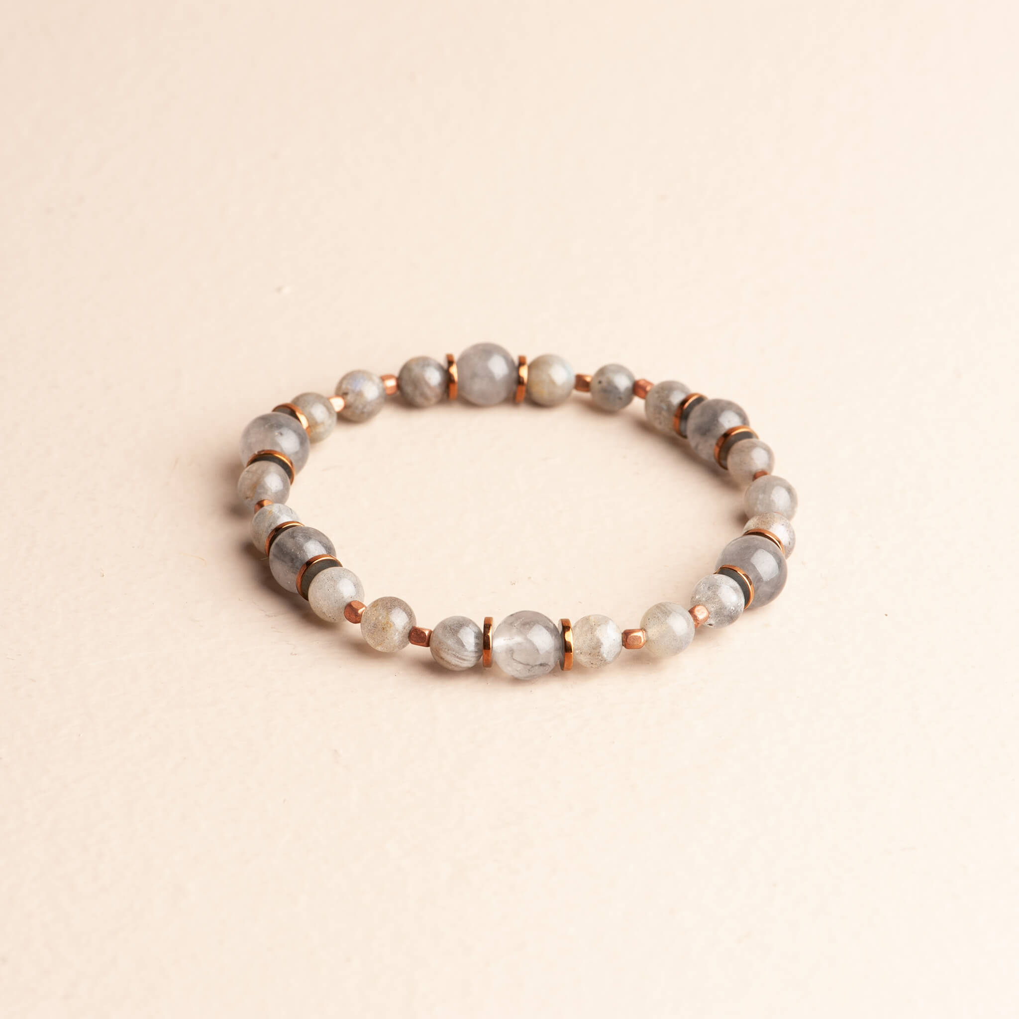 Delicate 7-inch stretch bracelet featuring graduating grey Labradorite beads with flash, separated by small copper spacer beads.