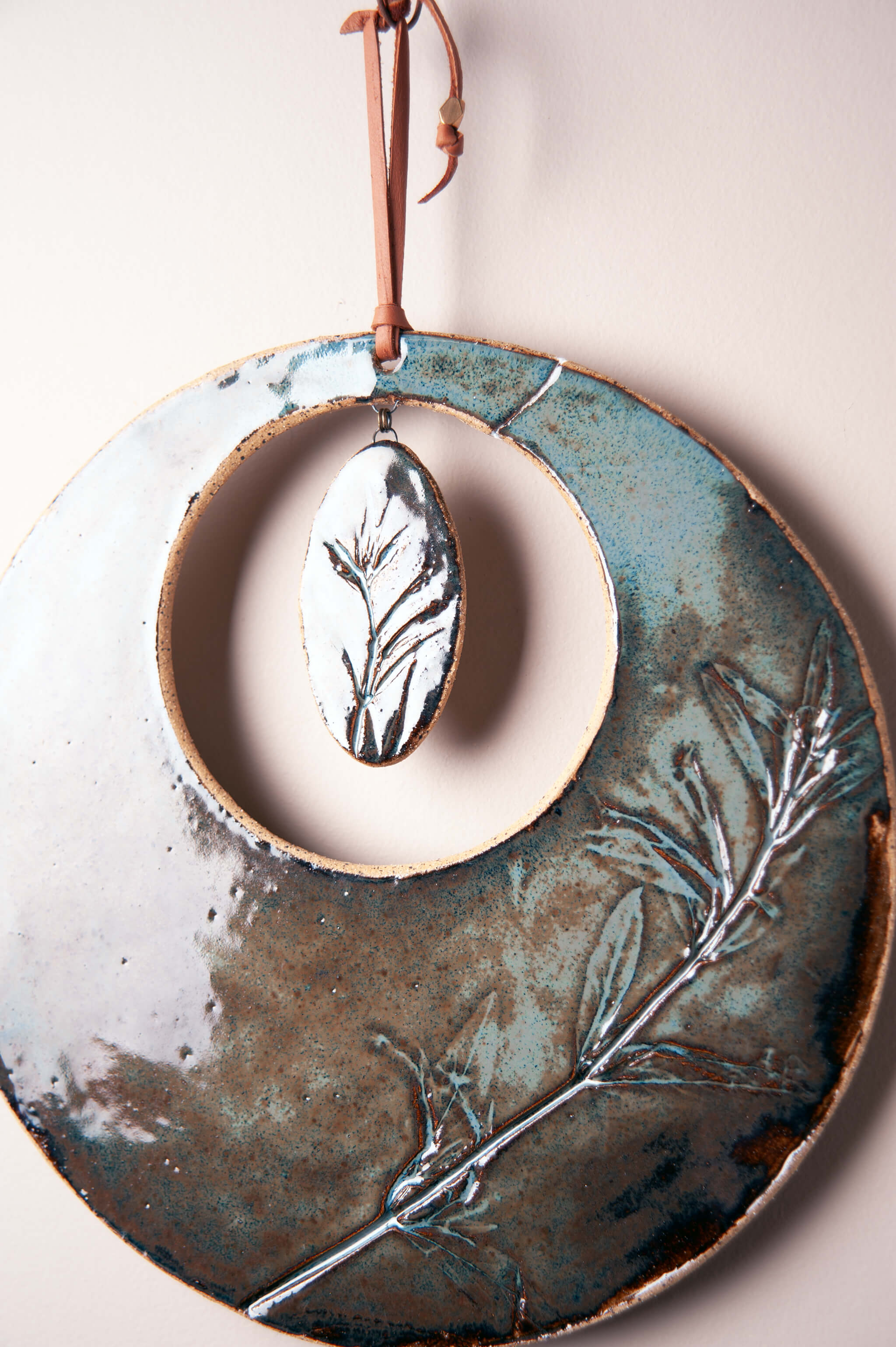 Detail of monkey flower impression filled with aqua marine glaze on handmade ceramic wall hanging by Jester Swink, Santa Cruz Mountains California