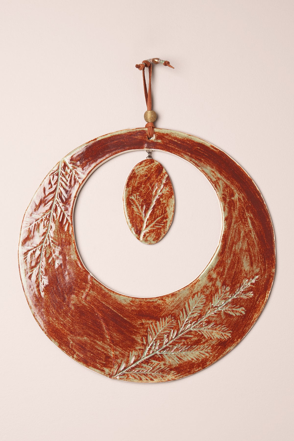 Large handmade circle ceramic wall hanging in Oolong glaze on Icelia porcelain with pressed redwood needle impressions and a brass dangle, kiln fired by Jester Swink Santa Cruz Mountains — From the Fire FTF_1026