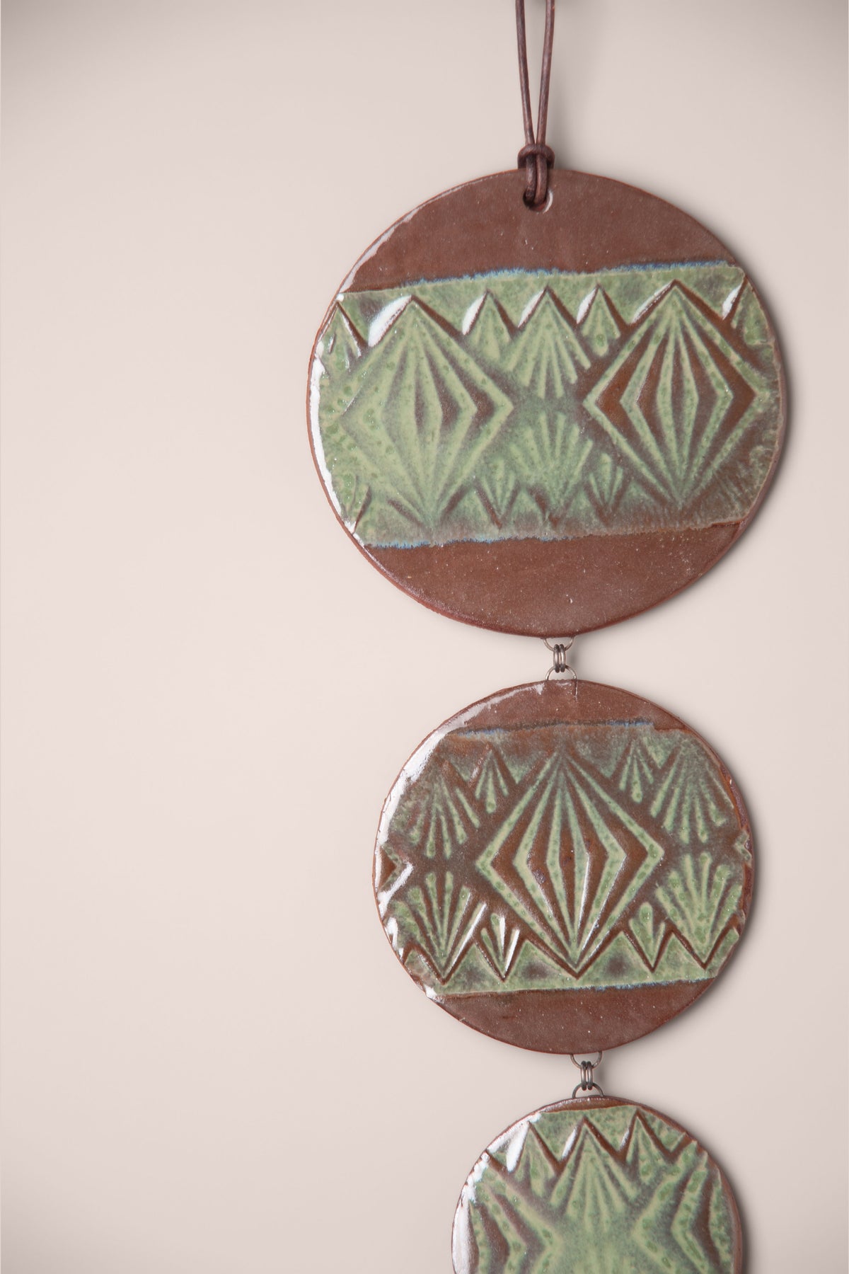 Detail of the pressed geometric pattern on a large handmade tiered ceramic wall hanging, kiln fired by Jester Swink, Santa Cruz Mountains California