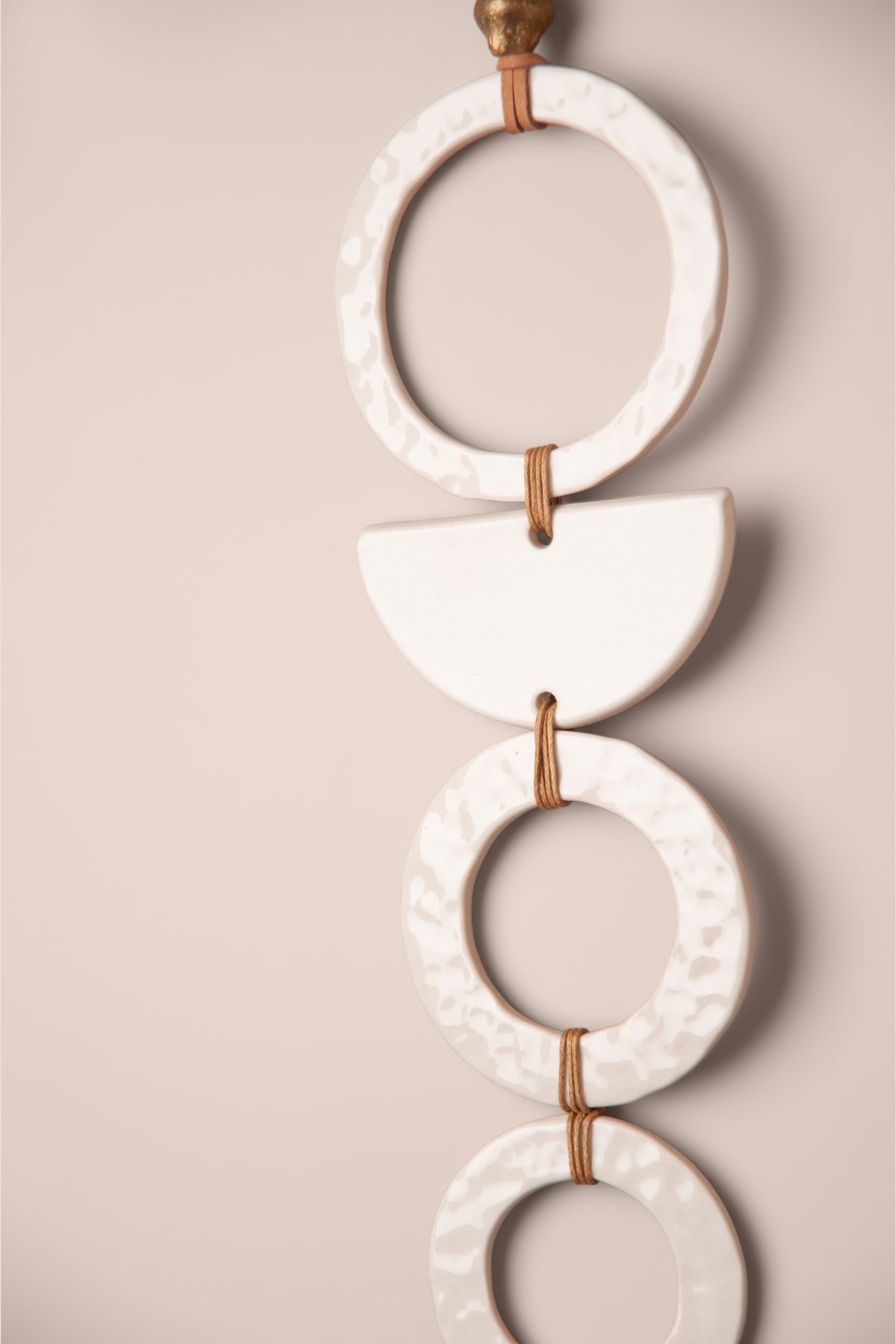Detail of the crater textured porcelain rings and half moon on a large handmade tiered ceramic wall hanging, kiln fired by Jester Swink, Santa Cruz Mountains California
