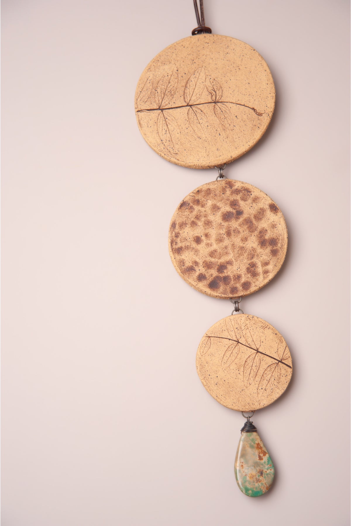Detail of the raw clay texture on the stepped discs of a large handmade tiered ceramic wall hanging, kiln fired by Jester Swink, Santa Cruz Mountains California