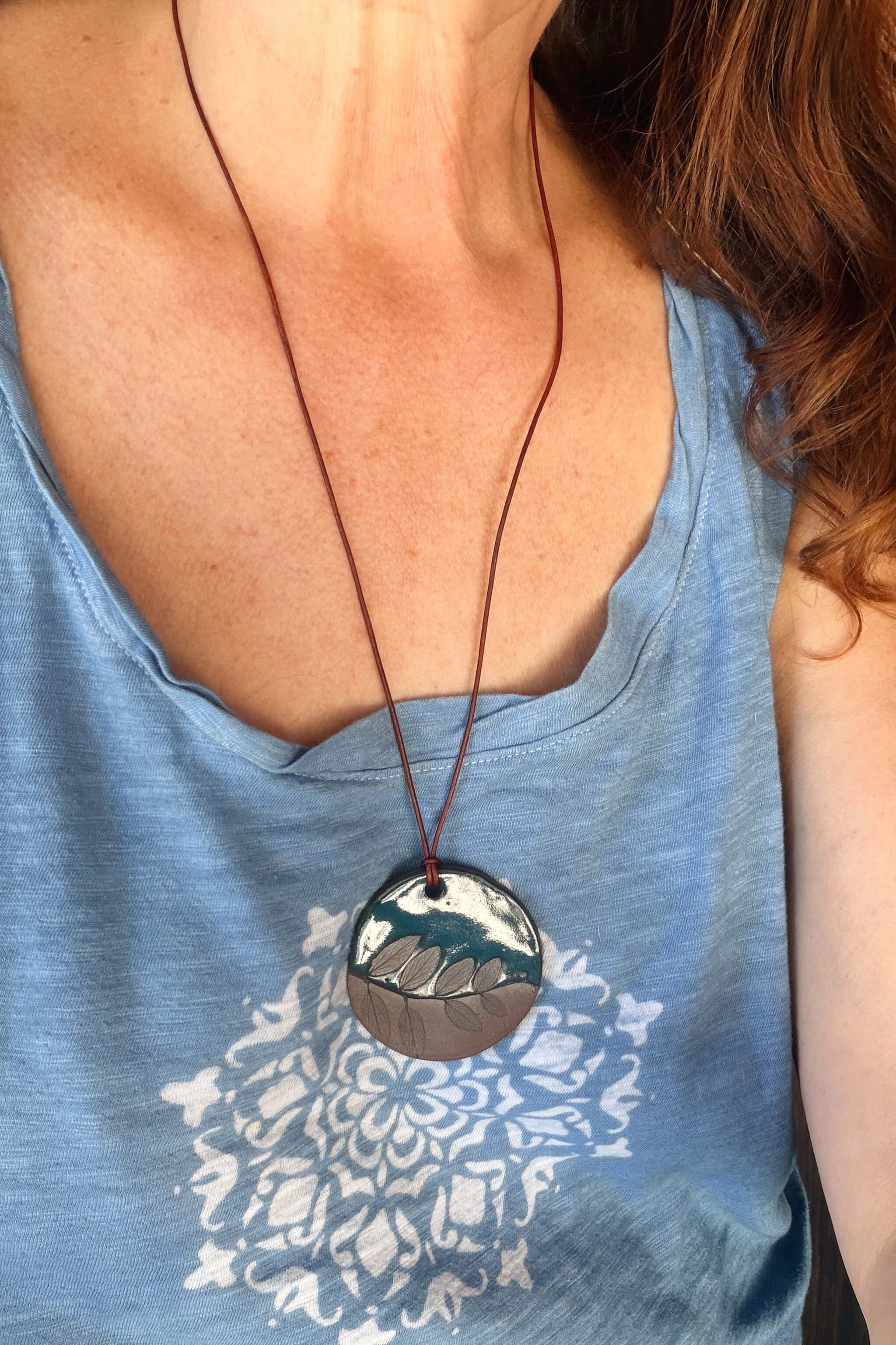 Handmade deep sea blue and terracotta ceramic leaf pendant necklace worn at long boho length on brown leather — From the Fire FTF_0726 by Jester Swink