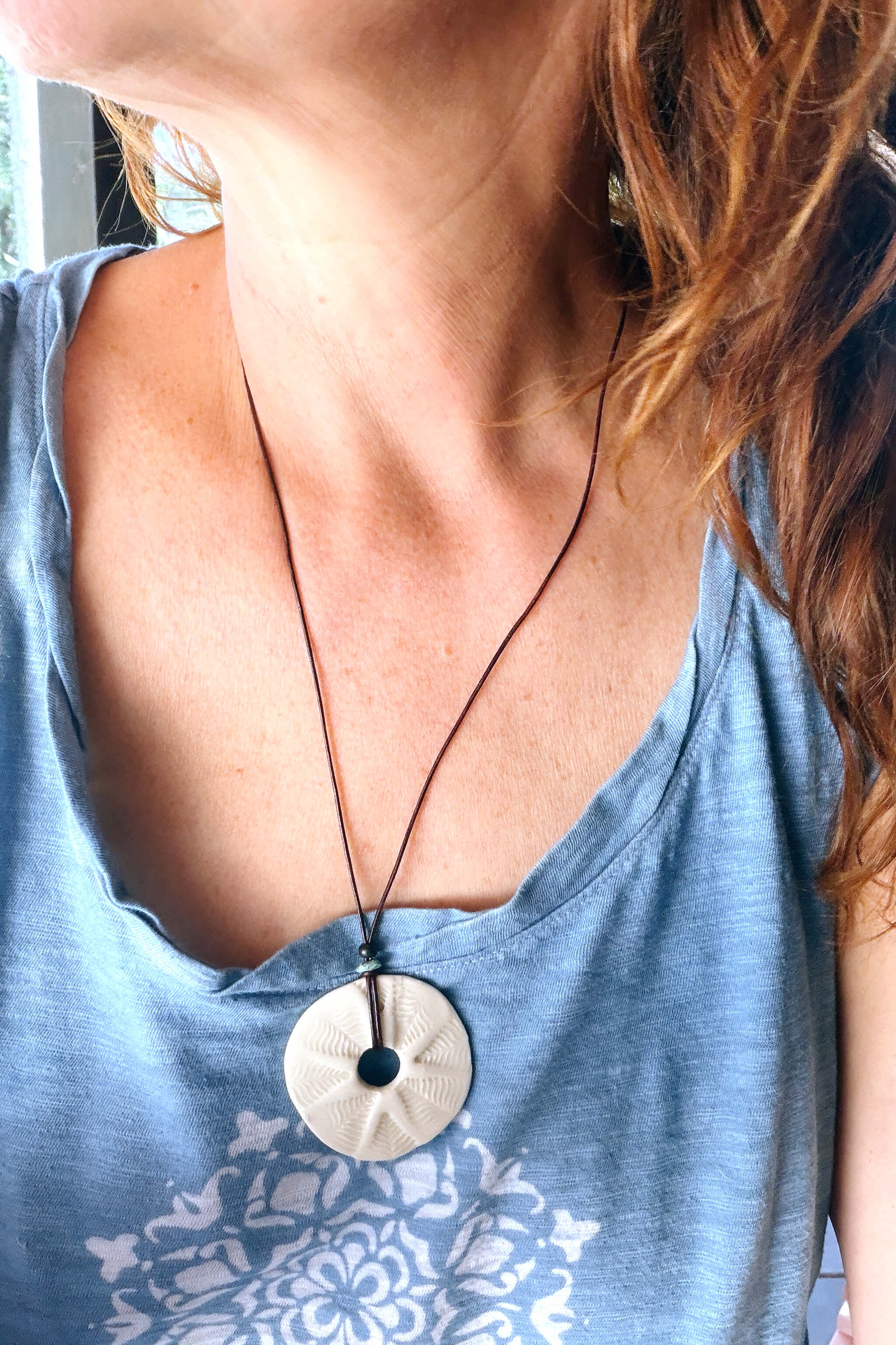 Handmade white ceramic leaf mandala pendant necklace worn at long boho length on dark chocolate leather — From the Fire FTF_0726 by Jester Swink