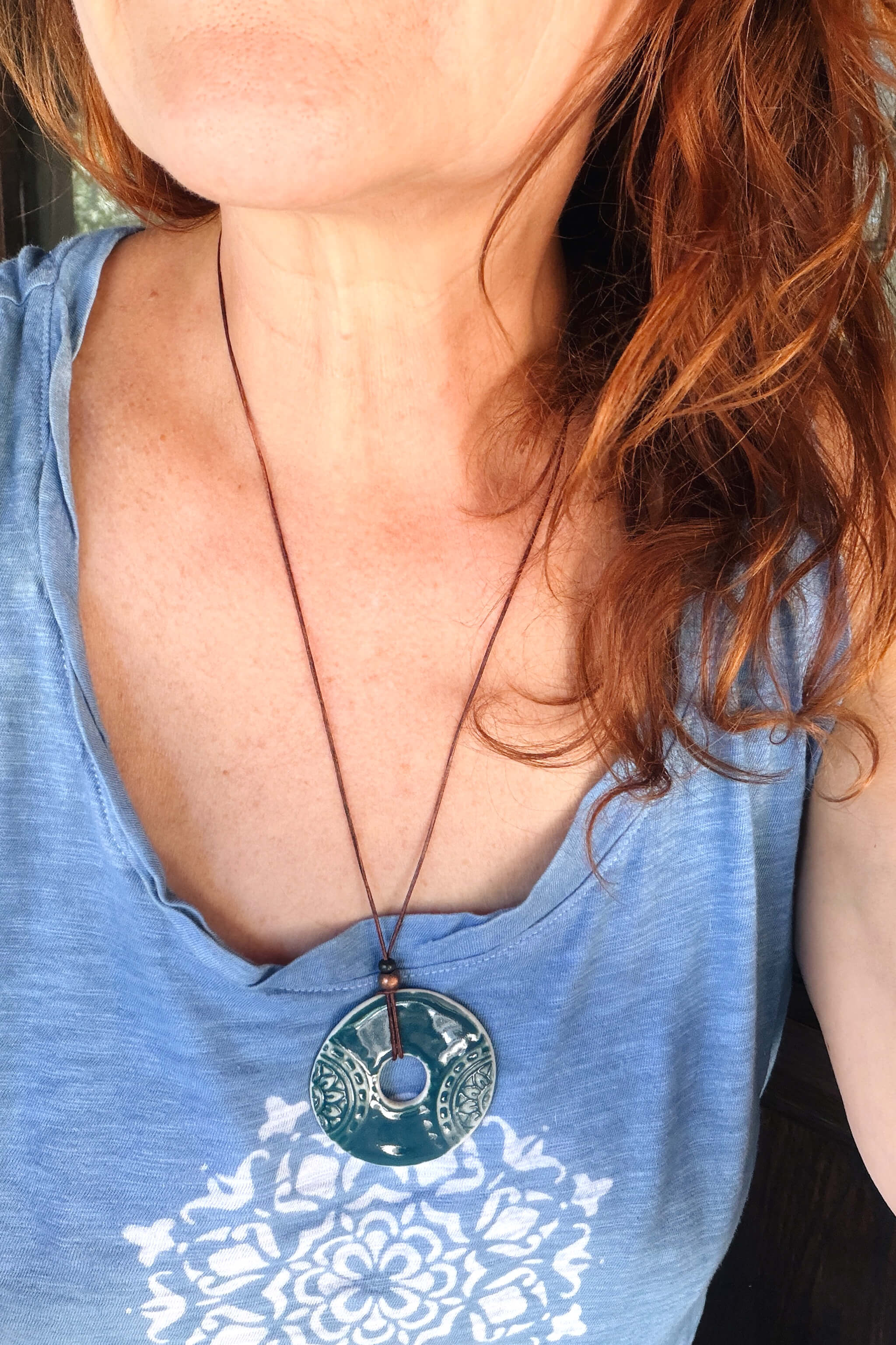 Handmade teal ceramic mandala pendant necklace worn at long boho length on dark Italian leather — From the Fire FTF_0726 by Jester Swink