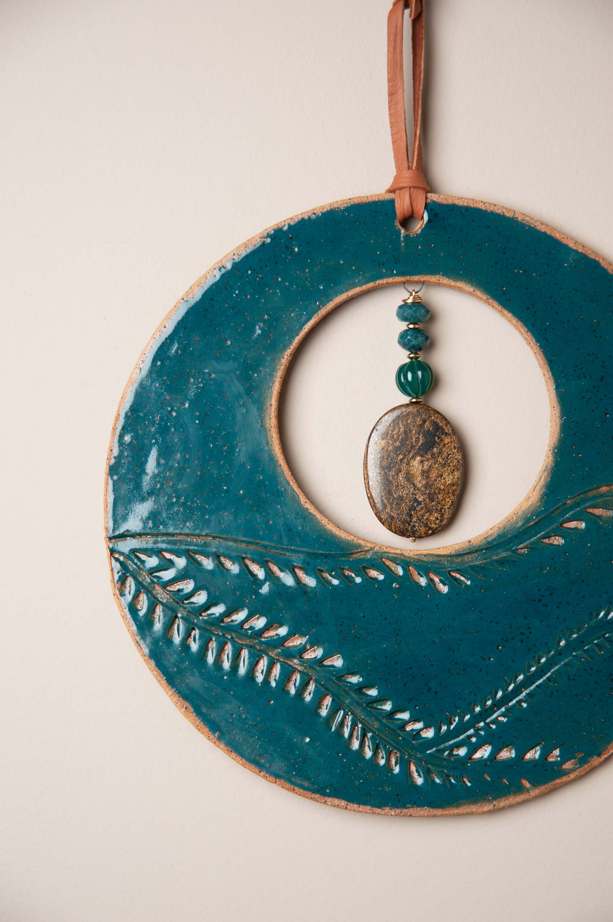Detail of hand pressed vine pattern with marine blue glaze on medium handmade ceramic wall hanging by Jester Swink, Santa Cruz Mountains California