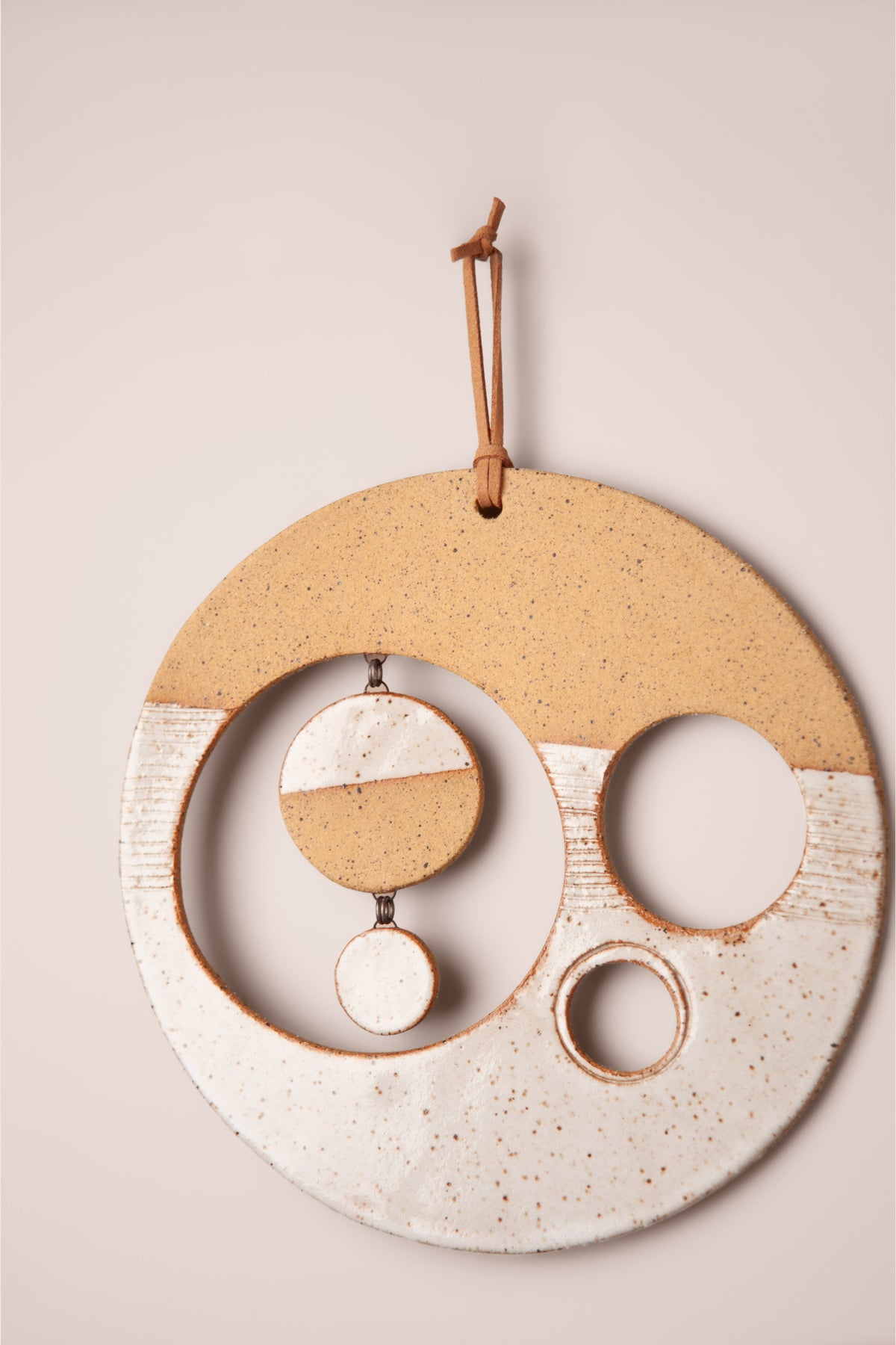 Detail of the white glaze and hanging moons on a medium handmade round ceramic wall hanging, kiln fired by Jester Swink, Santa Cruz Mountains California