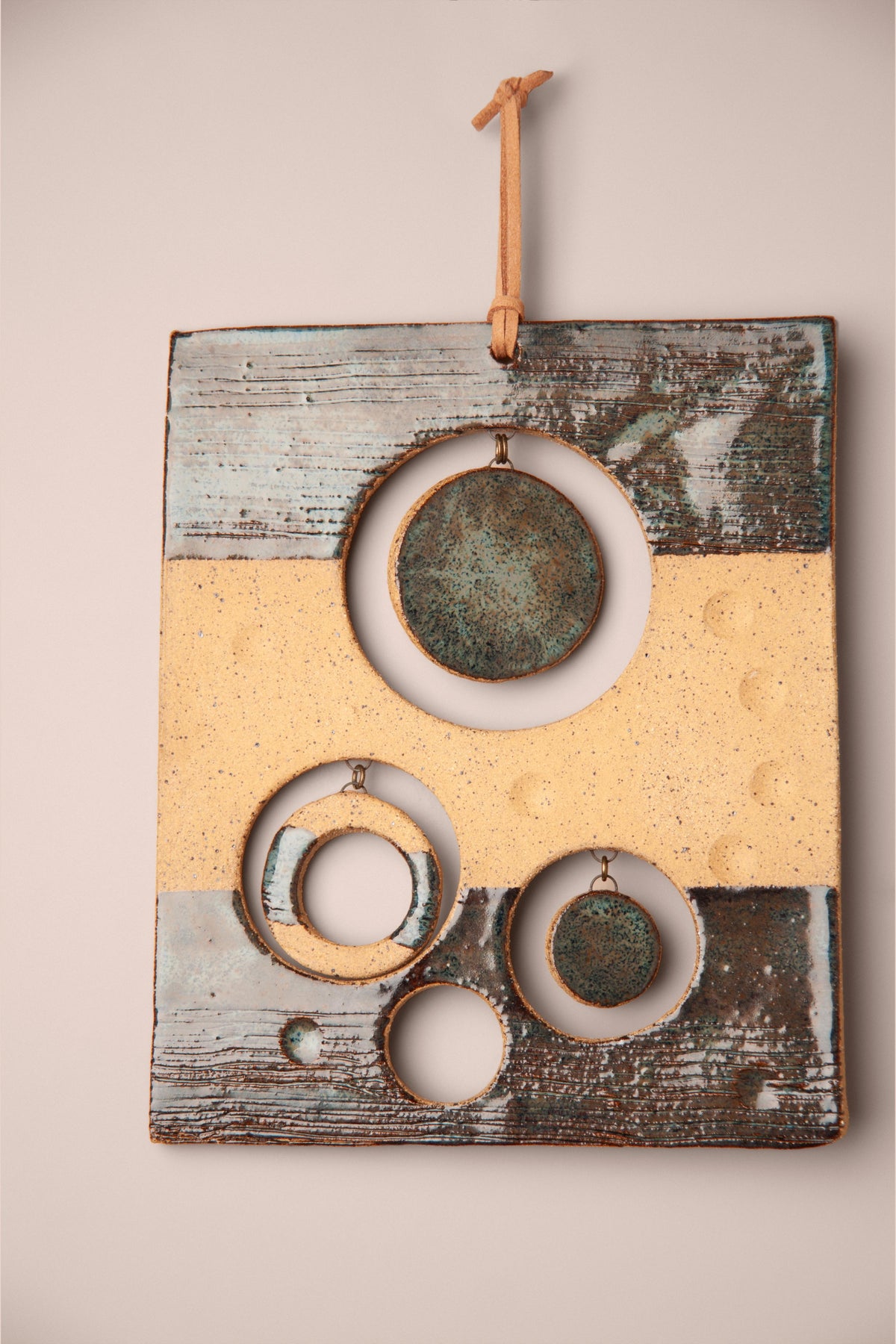 Detail of the clay stripe and hanging moons on a medium handmade rectangle ceramic wall hanging, kiln fired by Jester Swink, Santa Cruz Mountains California