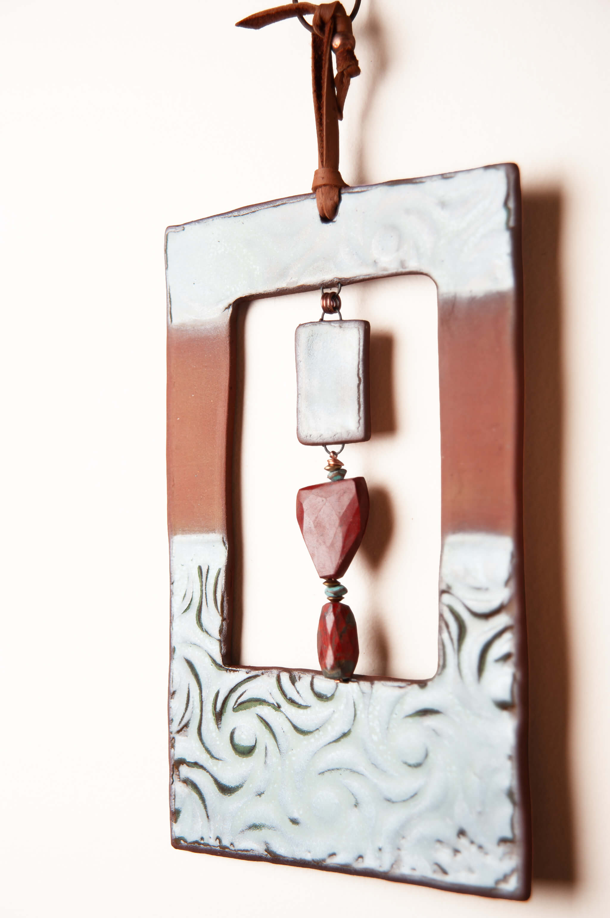 Detail of hand pressed swirl and dot pattern with antique aquamarine glaze on medium handmade rectangle ceramic wall hanging by Jester Swink, Santa Cruz Mountains California