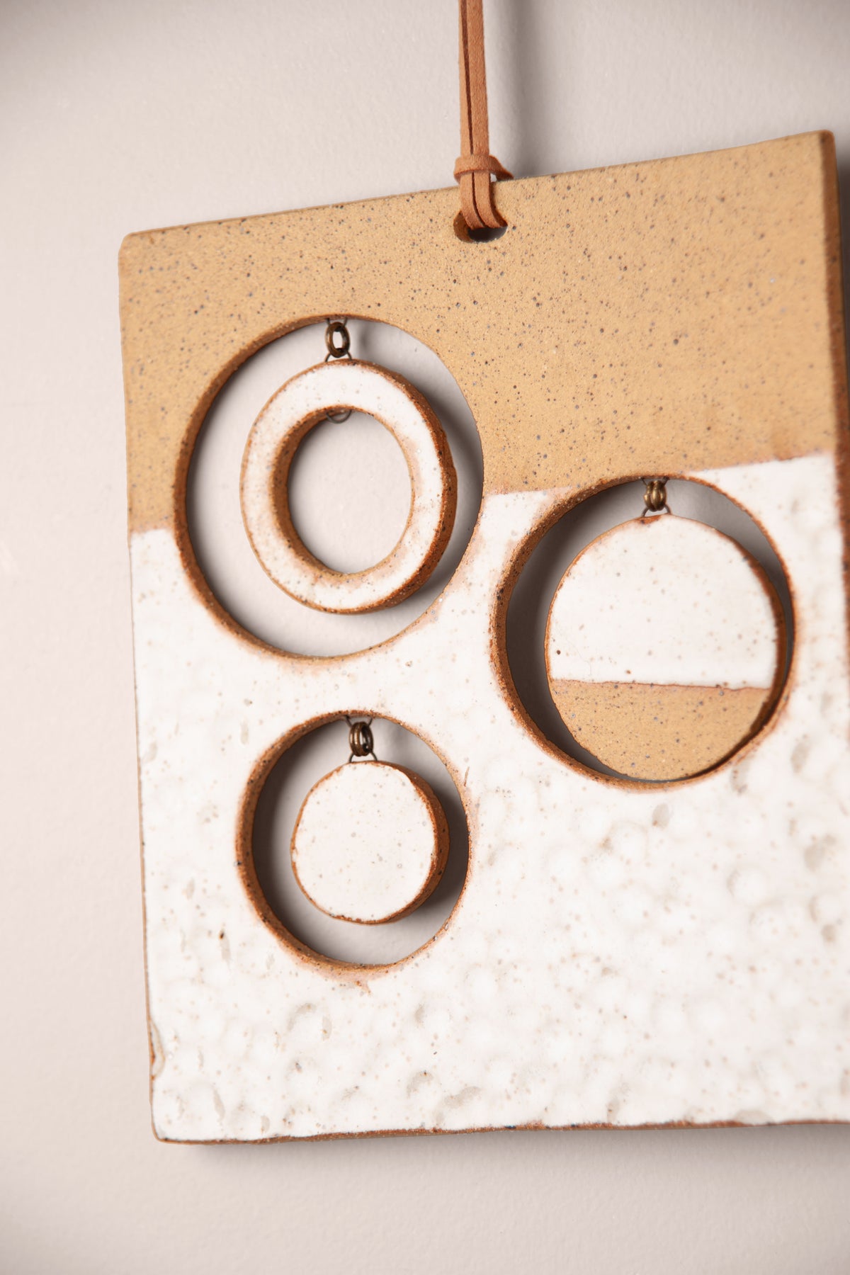Detail of the textured white glaze and hanging moons on a medium handmade rectangle ceramic wall hanging, kiln fired by Jester Swink, Santa Cruz Mountains California
