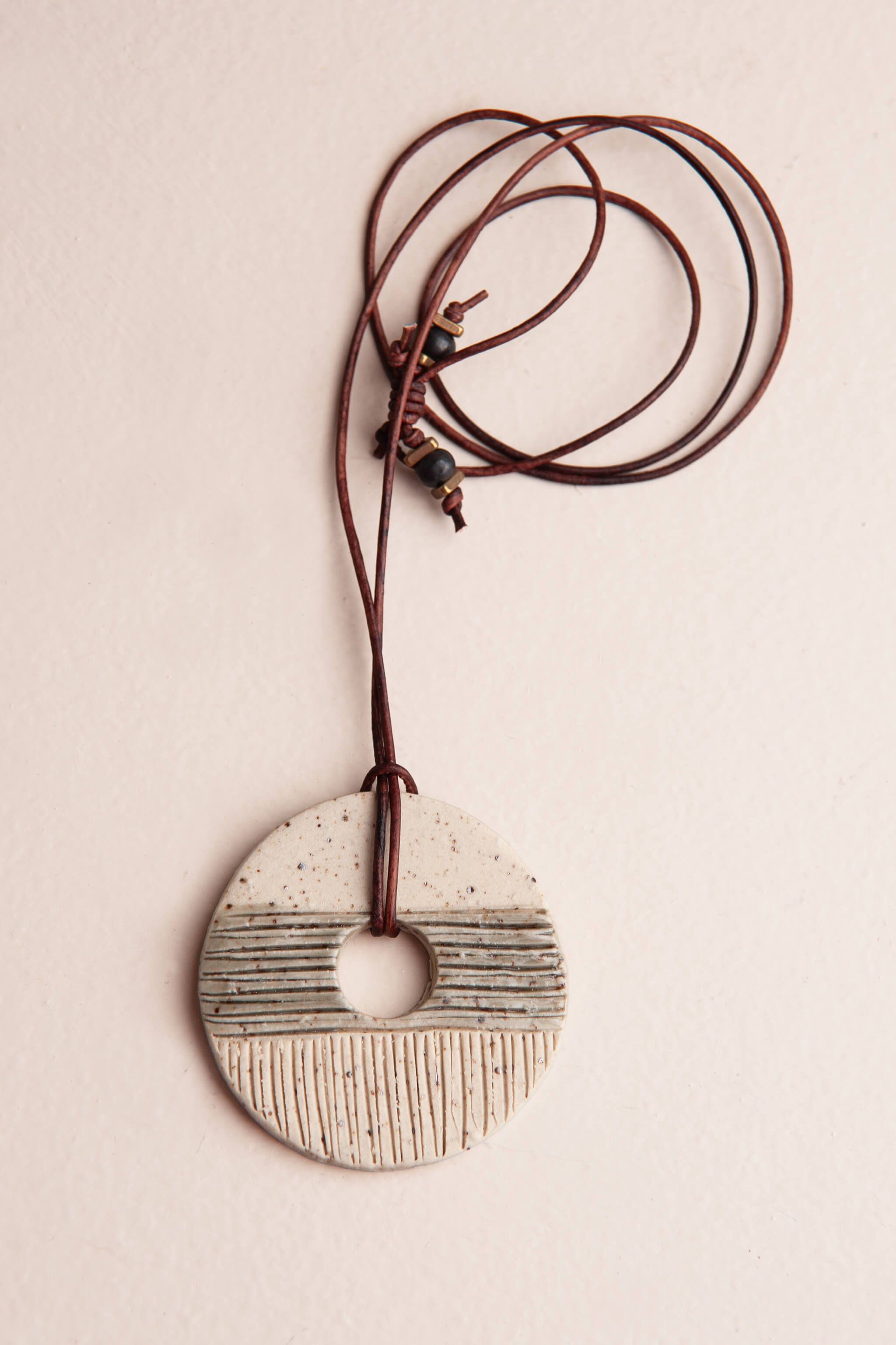 Handmade speckled white ceramic pendant necklace with carved lines and a smoke grey glaze band on reddish brown Italian leather, kiln fired by Jester Swink Santa Cruz Mountains — From the Fire FTF_0726