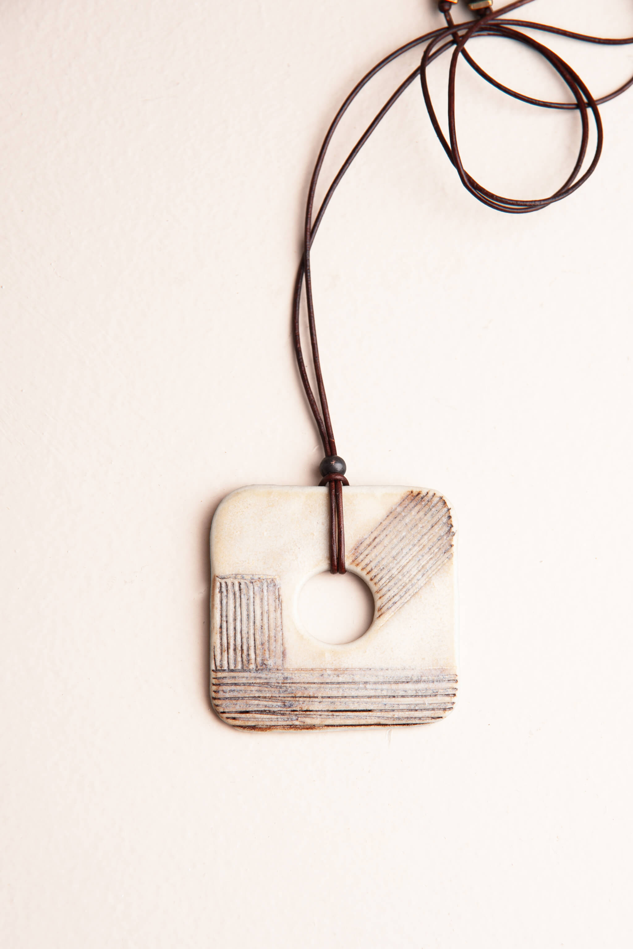 Handmade modern ceramic square pendant necklace in ivory porcelain with geometric line pattern on dark Italian leather, kiln fired by Jester Swink Santa Cruz Mountains — From the Fire FTF_0726