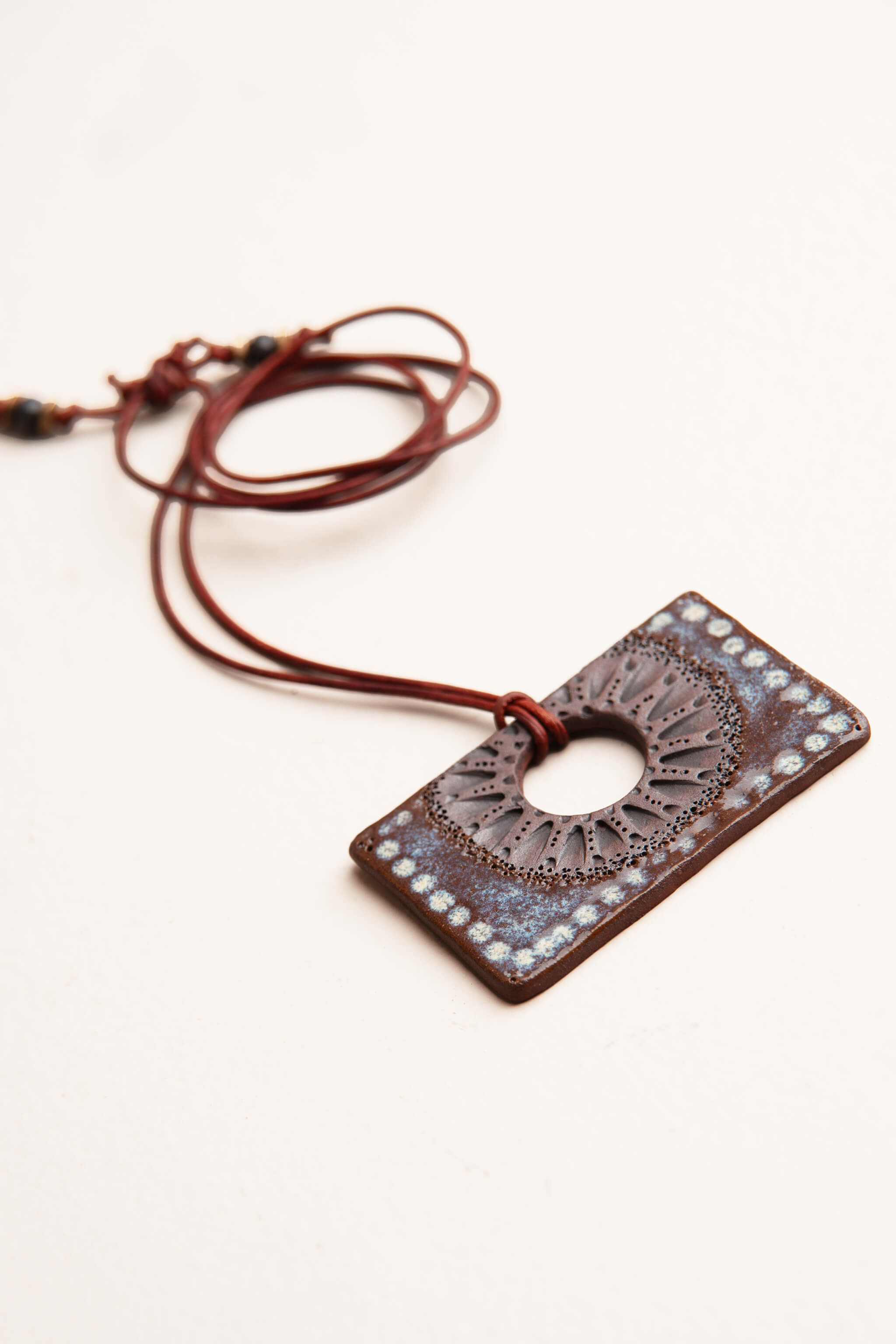 Angled detail of handmade ceramic rectangle pendant necklace showing raw terracotta body and sea breeze glaze dots — From the Fire FTF_0726 by Jester Swink