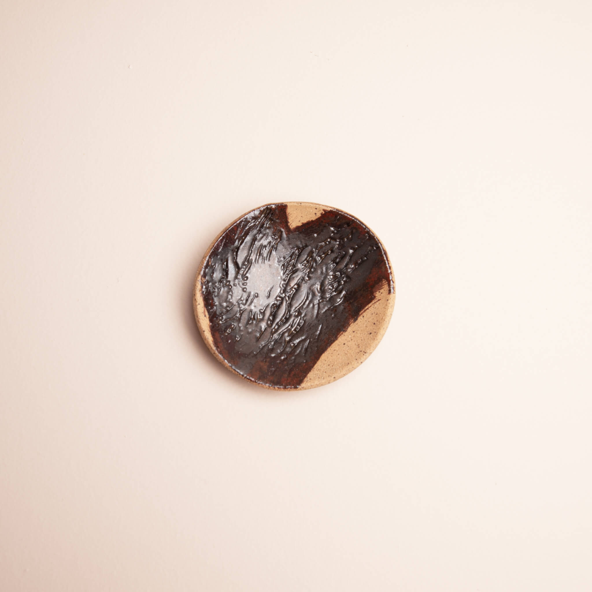 Overhead view of handmade ceramic Sierra Banksia ring dish with deep brown copper glaze and Banksia pod texture on speckled sierra clay, by Jester Swink