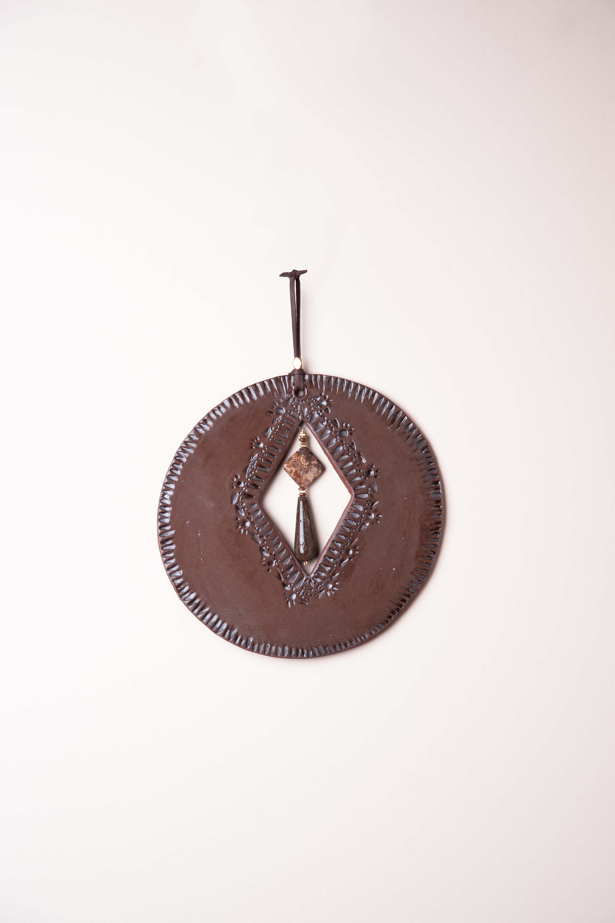 Small handmade circle ceramic wall art in chocolate brown with sunrise mountain tool pattern and fossilized coral agate drop, kiln fired by Jester Swink Santa Cruz Mountains — From the Fire FTF_0726