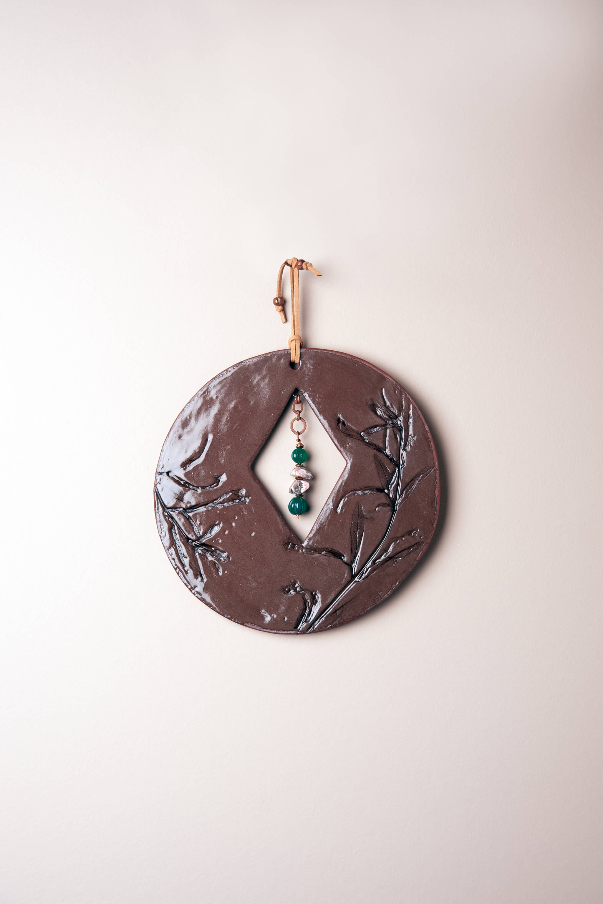 Small handmade circle ceramic wall art in chocolate brown with monkey flower impression, green onyx and rhodochrosite drop, kiln fired by Jester Swink Santa Cruz Mountains — From the Fire FTF_0726