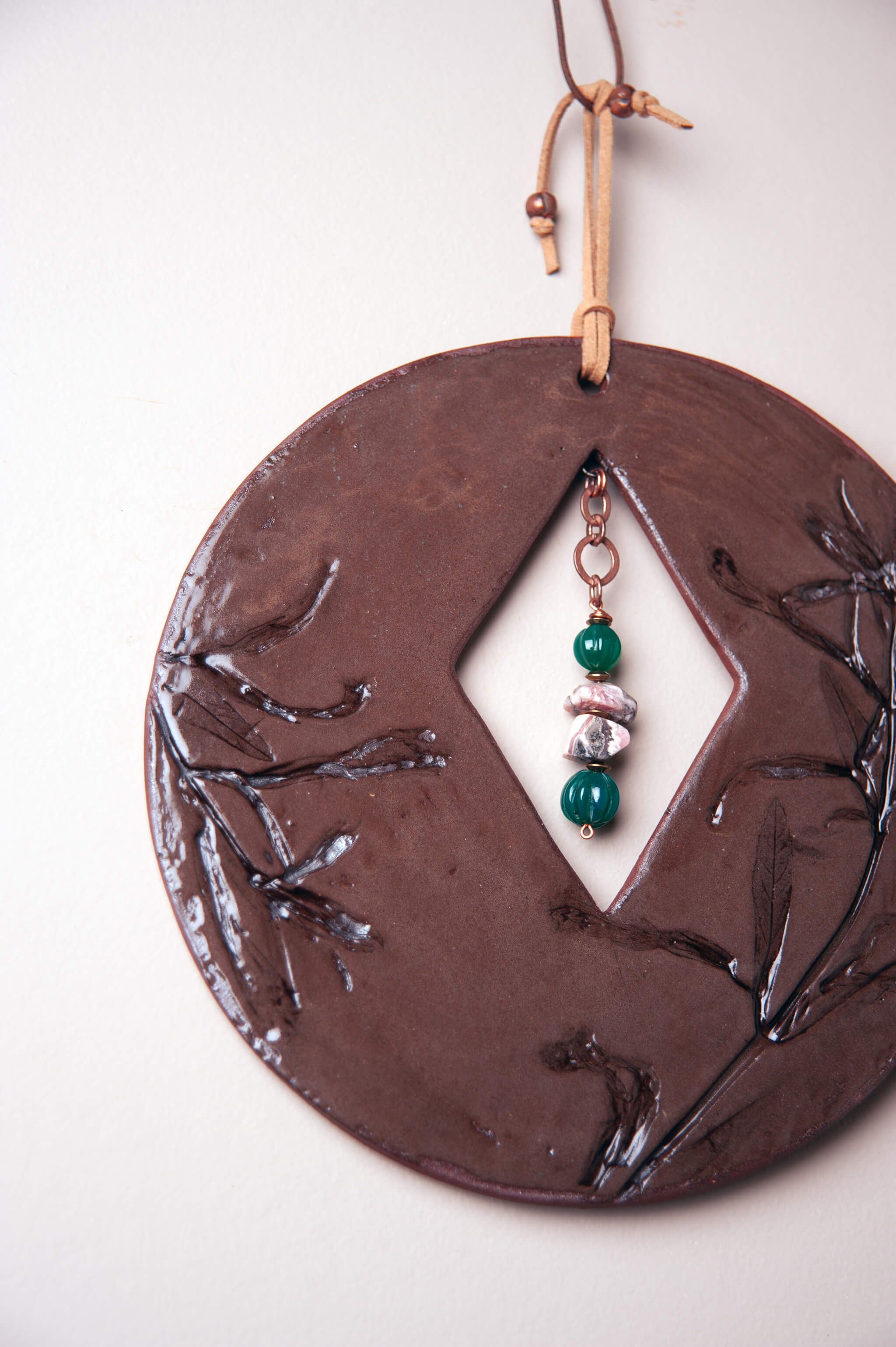 Detail of monkey flower impression and diamond cutout on small handmade ceramic wall art by Jester Swink, Santa Cruz Mountains California