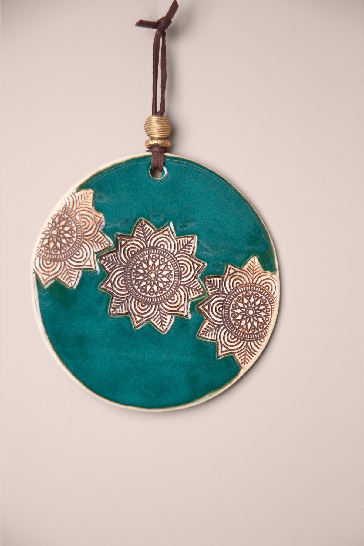 Detail of three pressed mandalas on a small handmade round ceramic wall hanging in Emerald glaze, kiln fired by Jester Swink, Santa Cruz Mountains California