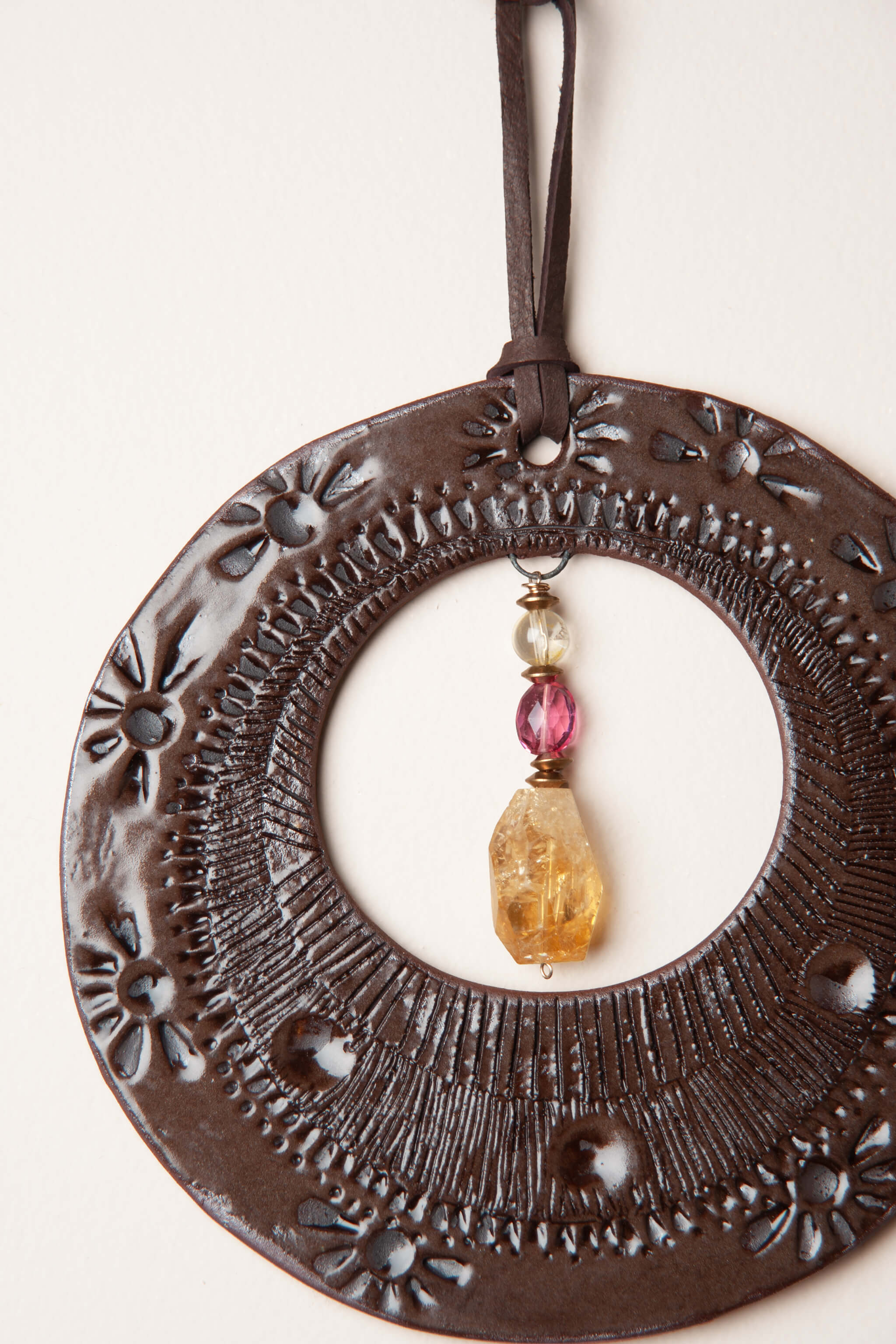 Detail of hand pressed sunburst and daisy border pattern on small handmade southwest ceramic wall hanging by Jester Swink, Santa Cruz Mountains California