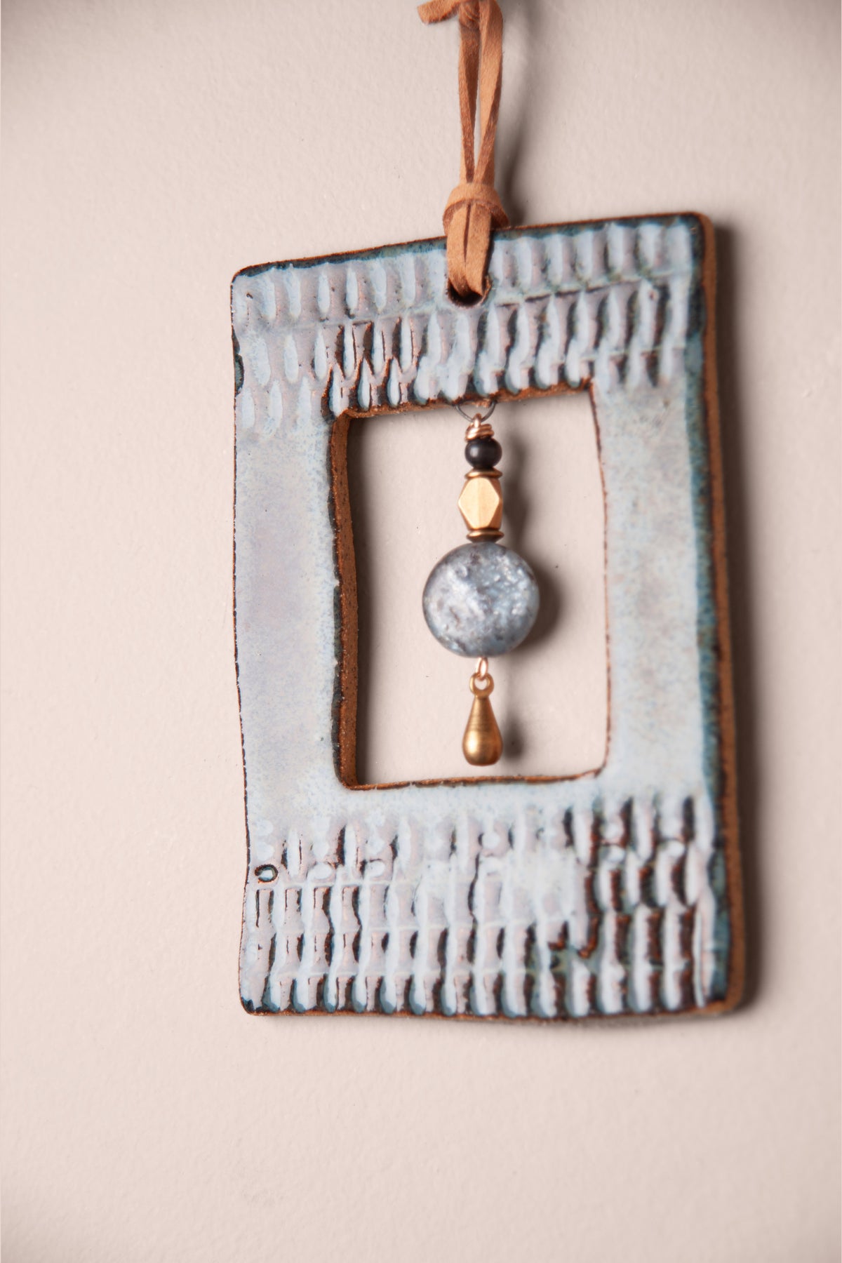 Detail of pressed ridges and the open window on a small handmade rectangle ceramic wall hanging, kiln fired by Jester Swink, Santa Cruz Mountains California