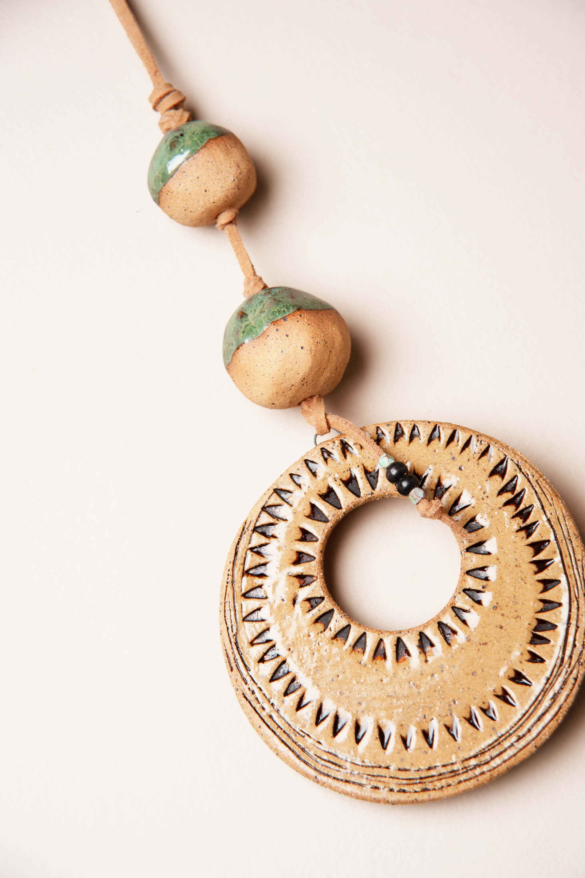 Detail of half glazed aqua marine ceramic beads and hand carved sun ray pattern on small handmade totem wall hanging by Jester Swink, Santa Cruz Mountains California