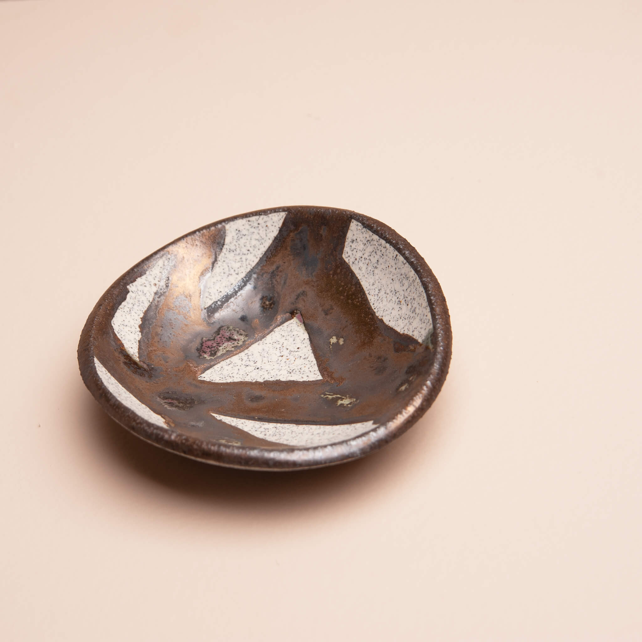 Handmade ceramic ring dish with gold brushstroke glaze, angled view showing depth and shape, dragon fruit clay, by Jester Swink