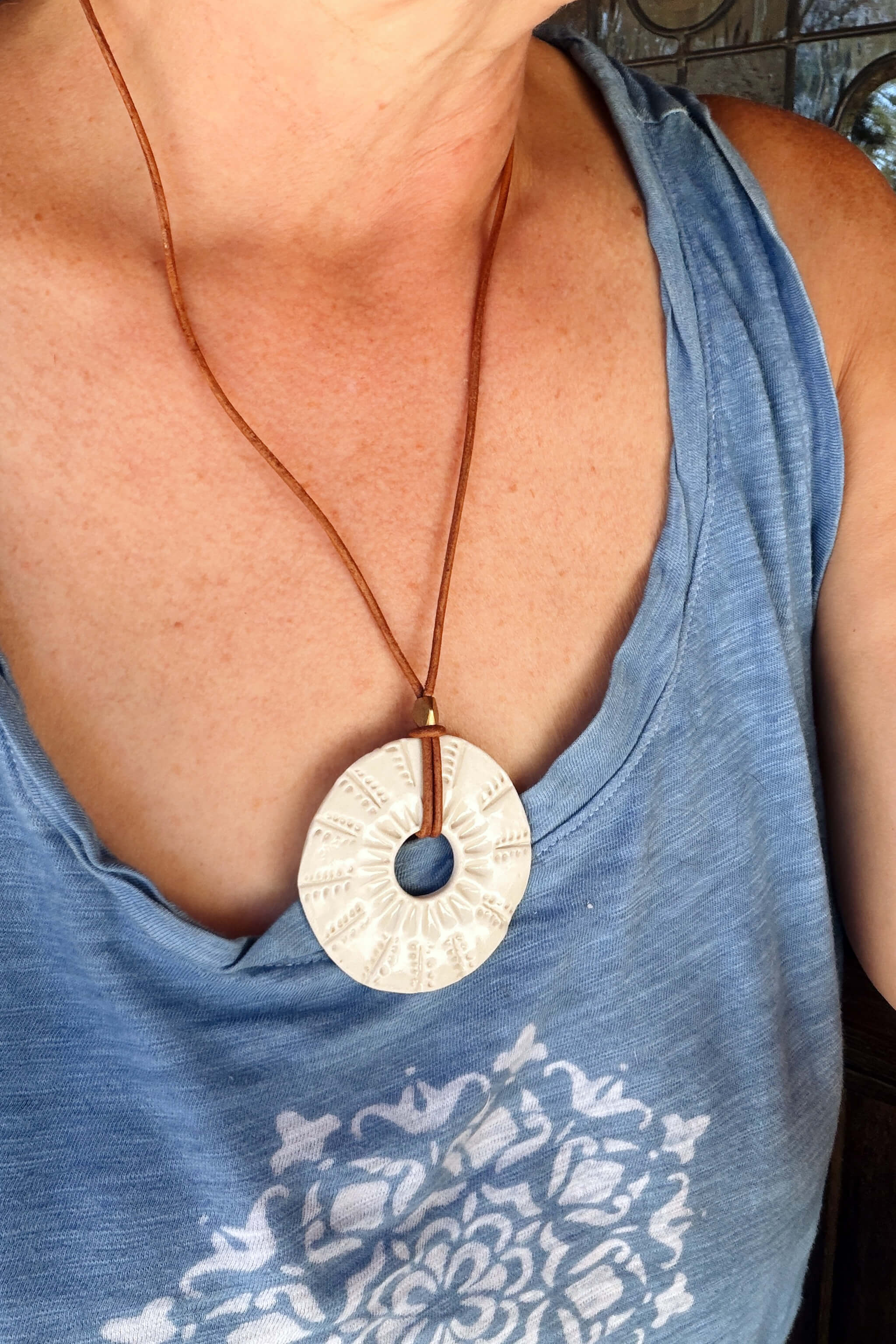 Handmade white ceramic sunburst pendant necklace worn at long boho length on Italian leather — From the Fire FTF_0726 by Jester Swink