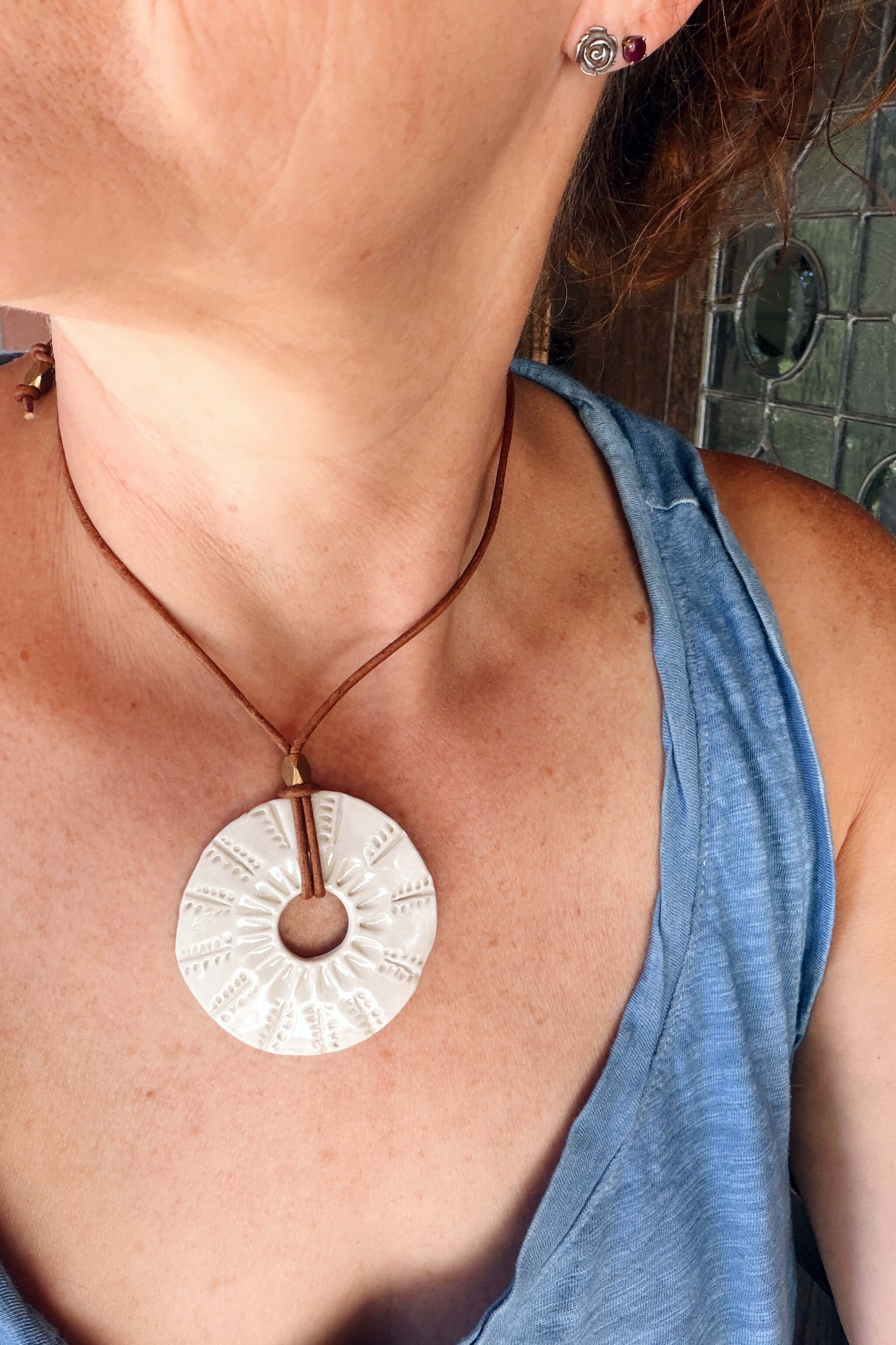 Handmade white ceramic sunburst pendant necklace worn at shorter length — minimalist ceramic jewelry From the Fire FTF_0726 by Jester Swink